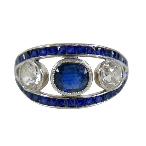 A platinum diamond and sapphire ring, the central sapphire approximately 0.53ct, flanked either side by a diamond, approximately 0.41ct each, with thirty four square cut sapphires to a split band, size O, 4.5g, with an insurance valuation for R46,800 dated 2015 (exchange at the time would have been $3,936).