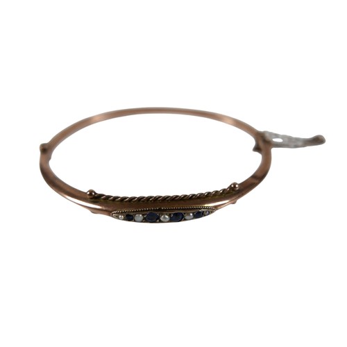 41 - An Edward VII rose gold hinged bangle, set with a row of four round faceted cut sapphires and seed p... 