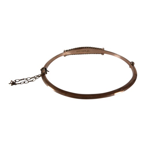 41 - An Edward VII rose gold hinged bangle, set with a row of four round faceted cut sapphires and seed p... 