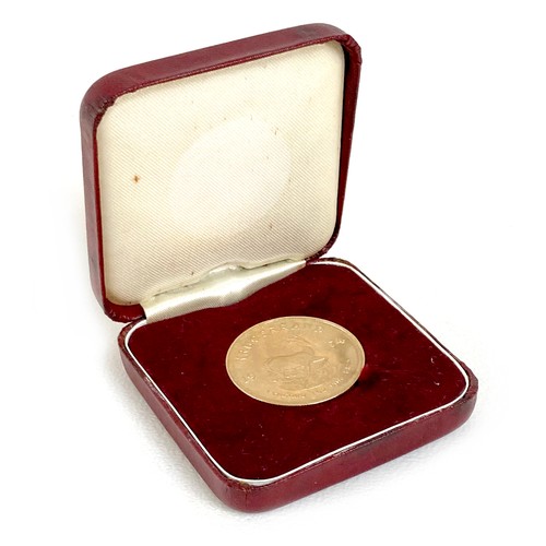 105 - A 22ct gold South African Krugerrand, 1974, 'Fyngoud 1oz Fine Gold', 32.5mm, 33.8g, in burgundy colo... 