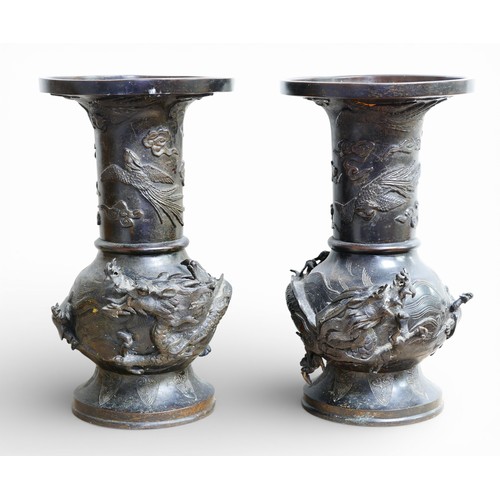 311 - A pair of Oriental bronze dragon urns, each decorated in high relief with a dragon chasing a flaming... 