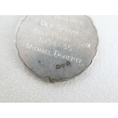 87 - A small group of silver and white metal jewellery, including a charm bracelet, two rings, sports med... 
