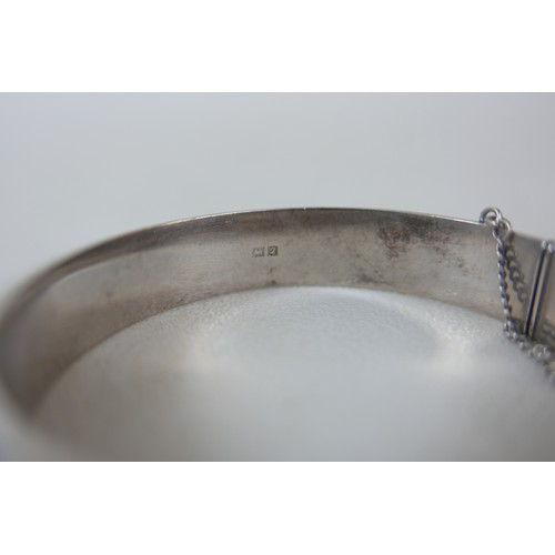 87 - A small group of silver and white metal jewellery, including a charm bracelet, two rings, sports med... 