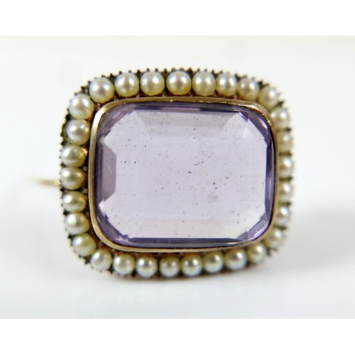 44 - A yellow metal mourning brooch with a central amethyst surrounded by seed pearls, 23 by 20 by 12mm, ... 