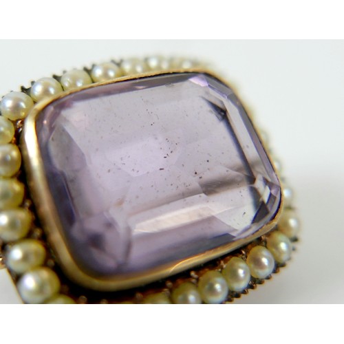 44 - A yellow metal mourning brooch with a central amethyst surrounded by seed pearls, 23 by 20 by 12mm, ... 