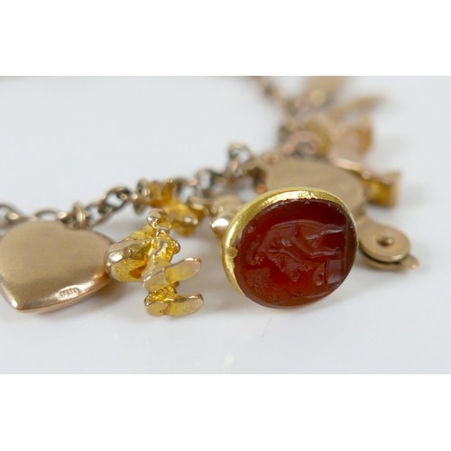 11 - A 9ct yellow gold charm bracelet with twenty charms, 35.3g.
