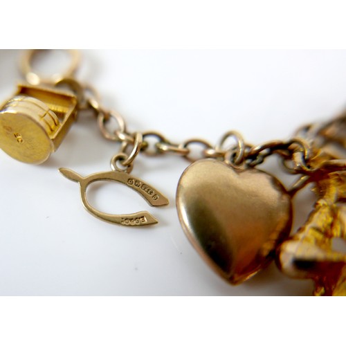 11 - A 9ct yellow gold charm bracelet with twenty charms, 35.3g.
