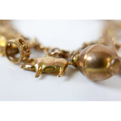 11 - A 9ct yellow gold charm bracelet with twenty charms, 35.3g.