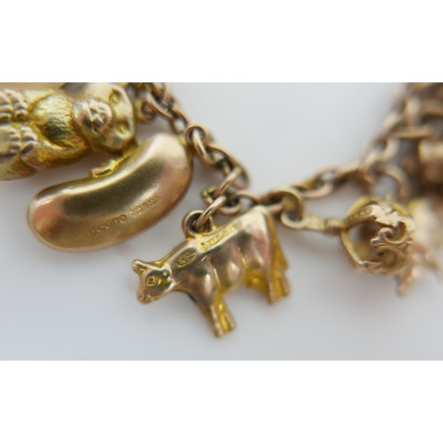 11 - A 9ct yellow gold charm bracelet with twenty charms, 35.3g.
