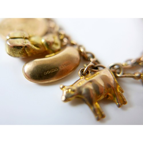 11 - A 9ct yellow gold charm bracelet with twenty charms, 35.3g.