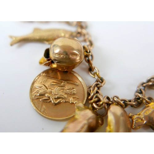 11 - A 9ct yellow gold charm bracelet with twenty charms, 35.3g.