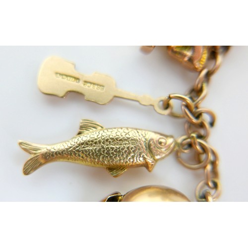 11 - A 9ct yellow gold charm bracelet with twenty charms, 35.3g.