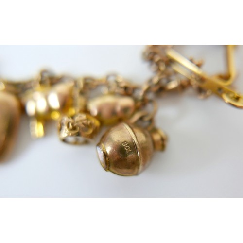 11 - A 9ct yellow gold charm bracelet with twenty charms, 35.3g.
