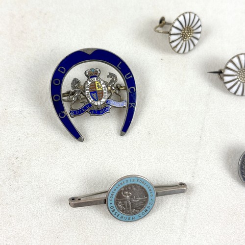 41 - An interesting group of six brooches, comprising a silver and white enamelled brooch with three flow... 