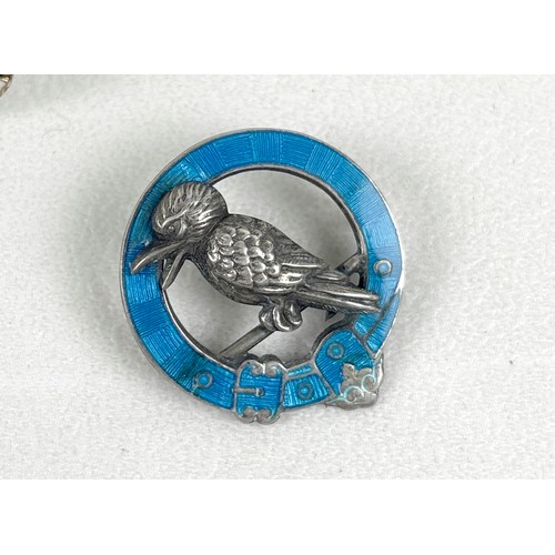 41 - An interesting group of six brooches, comprising a silver and white enamelled brooch with three flow... 