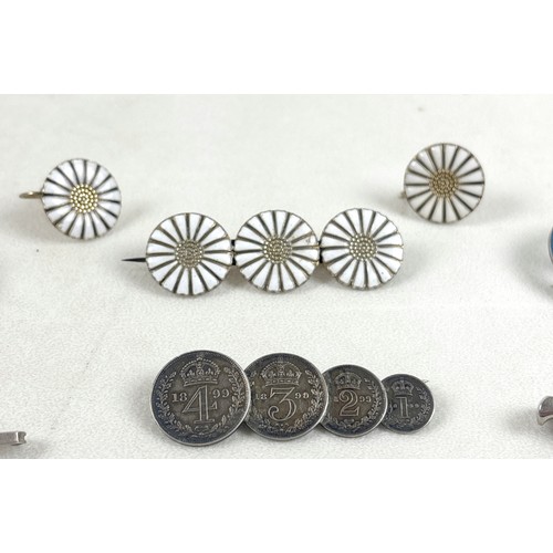 41 - An interesting group of six brooches, comprising a silver and white enamelled brooch with three flow... 