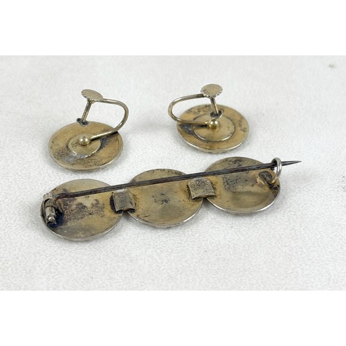41 - An interesting group of six brooches, comprising a silver and white enamelled brooch with three flow... 
