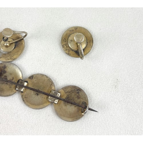 41 - An interesting group of six brooches, comprising a silver and white enamelled brooch with three flow... 