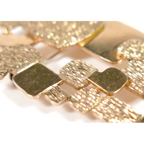 5 - An 18ct yellow gold abstract design brooch part textured marked NM, 57 by 32mm, 15.2g.