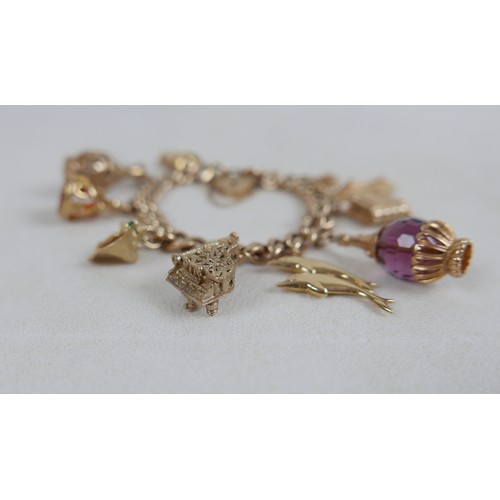 1 - A 9ct gold charm bracelet, flat curb, with assorted 9ct and 14ct gold charms including dolphins, bib... 