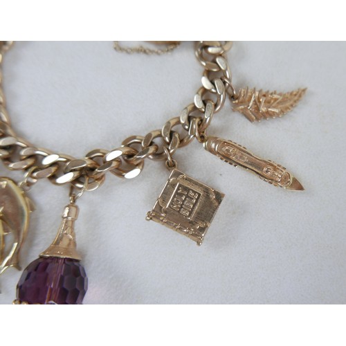 1 - A 9ct gold charm bracelet, flat curb, with assorted 9ct and 14ct gold charms including dolphins, bib... 