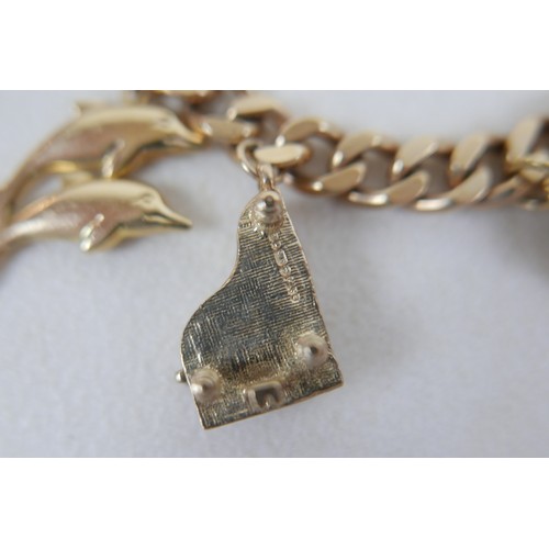 1 - A 9ct gold charm bracelet, flat curb, with assorted 9ct and 14ct gold charms including dolphins, bib... 