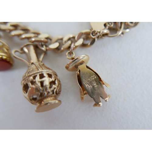 1 - A 9ct gold charm bracelet, flat curb, with assorted 9ct and 14ct gold charms including dolphins, bib... 
