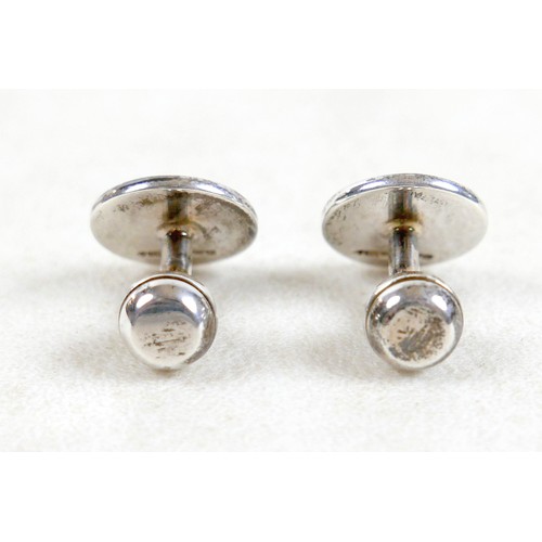 18 - A pair of modern silver cufflinks, ball return style with circular fronts decorated in a swirling de... 