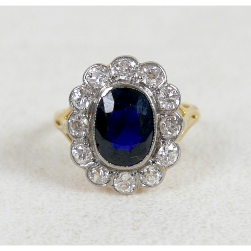 6 - An 18ct gold and platinum set sapphire and diamond flowered ring, size L / M, the oval cushion cut s... 