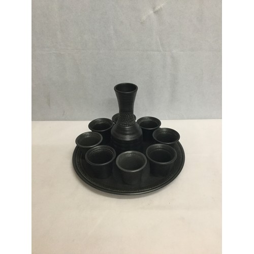 502 - Black stoneware decanter along with matching cups and tray.