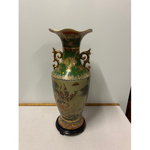 112 - Large hand painted Oriental vase on wooden plinth damage to lip of vase. 62cm tall.