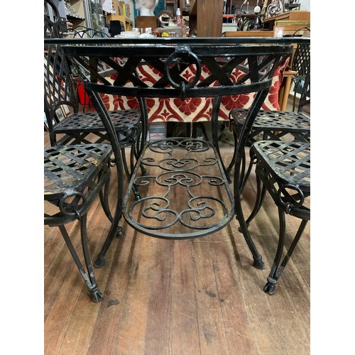 114 - Large metal garden table with glass top 153cm long and trestle design along with 4 matching chairs.