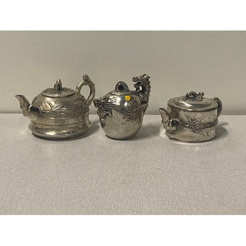 5 - 3 Chinese white metal teapots, 1 with dragon design & 2 with foliage, all stamped to the base.
