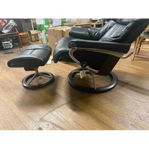 291 - Black leather Stressless arm chair with matching stool.