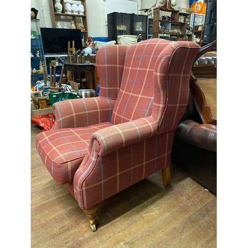 67 - Wingback chair on wooden legs and brass casters upholstered in red check pattern.