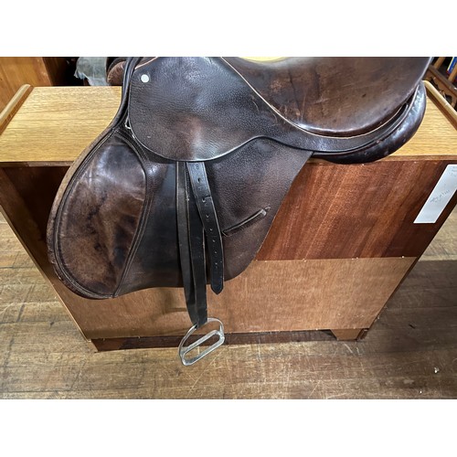 257 - Leather saddle with stirrups.