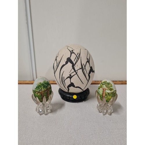 24 - Ostrich egg hand painted with tribal hunters on ebony wooden stand along with pair of hand painted e... 