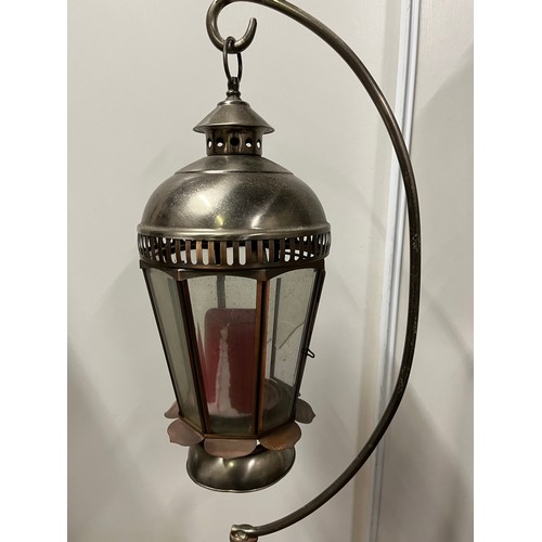 69 - Pair of graduated metal outdoor lantern stands with glass lanterns. Copper finish on curved foot sta... 