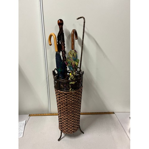 101 - Wicker and metal umbrella stand with umbrellas and walking sticks.