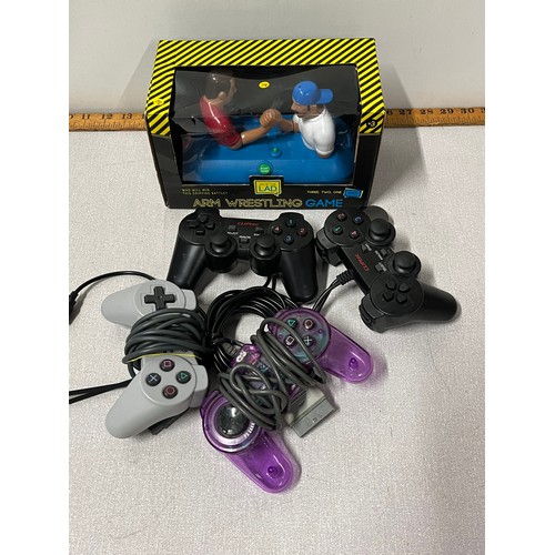 425 - 4 Playstation controllers & boxed arm wrestling game.