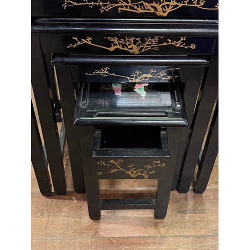 41 - a nest of 4 black lacquered oriental tables with mother of pearl inlay with glass protectors