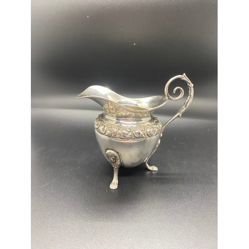 6 - silver hallmarked cream jug with scroll handle & fruit design on possibly lion feet 110 grams