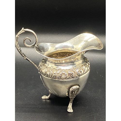 6 - silver hallmarked cream jug with scroll handle & fruit design on possibly lion feet 110 grams