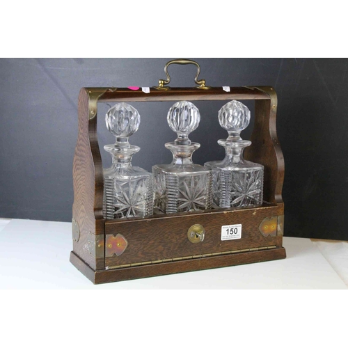 150 - Oak and Brass Mounted Tantalus with three matching decanters, with key, 34cms wide x 29.5cms high