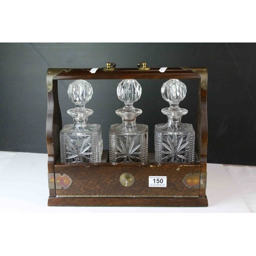 150 - Oak and Brass Mounted Tantalus with three matching decanters, with key, 34cms wide x 29.5cms high