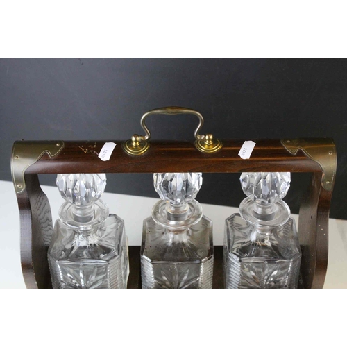 150 - Oak and Brass Mounted Tantalus with three matching decanters, with key, 34cms wide x 29.5cms high