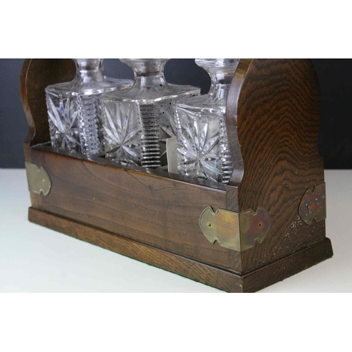 150 - Oak and Brass Mounted Tantalus with three matching decanters, with key, 34cms wide x 29.5cms high