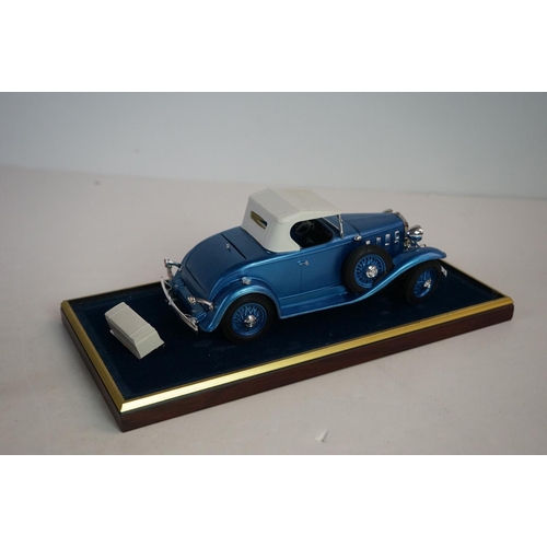 1169 - Five cased 1:18 scale diecast model classic cars to include BMW, Jaguar etc, models fixed to a woode... 