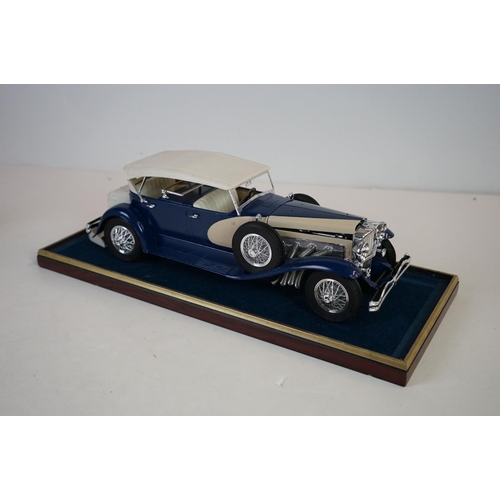 1169 - Five cased 1:18 scale diecast model classic cars to include BMW, Jaguar etc, models fixed to a woode... 