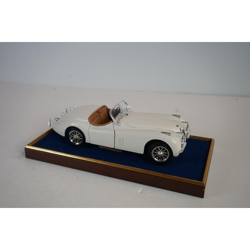 1169 - Five cased 1:18 scale diecast model classic cars to include BMW, Jaguar etc, models fixed to a woode... 